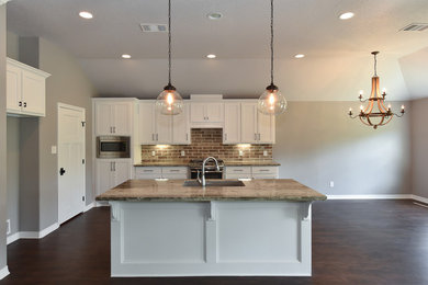 Example of a large minimalist single-wall vinyl floor open concept kitchen design in Austin with an undermount sink, shaker cabinets, white cabinets, granite countertops, brown backsplash, stone tile backsplash, stainless steel appliances and an island