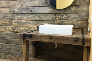 Design ideas for a mid-sized country bathroom in DC Metro with distressed cabinets, a one-piece toilet, beige tile, travertine, ceramic floors, a console sink, wood benchtops, beige floor, a sliding shower screen, brown benchtops, a single vanity, a freestanding vanity and wood walls.