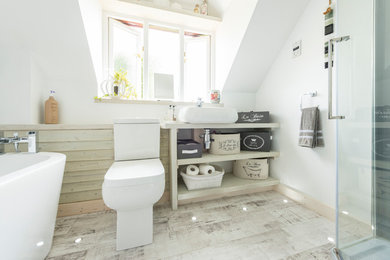 This is an example of a small contemporary kids bathroom in Dorset with a freestanding tub, a corner shower, grey walls, laminate floors, grey floor, a hinged shower door, a one-piece toilet and a vessel sink.