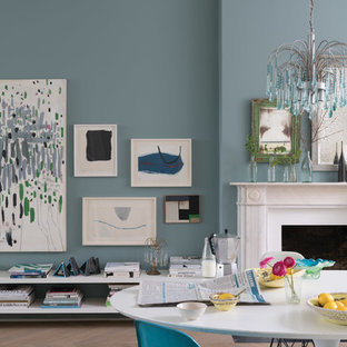 ニュルンベルクの中サイズのエクレクティックスタイルのLDKの画像 (青い壁、無垢フローリング、標準型暖炉、石材の暖炉まわり、茶色い床)