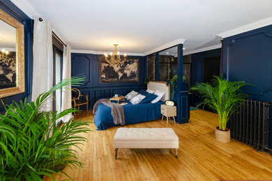 Cette image montre une grande chambre parentale avec un mur bleu et parquet clair.