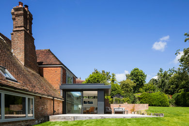 Inspiration for a large and black rural two floor rear house exterior in Sussex with a hip roof, a tiled roof and a red roof.