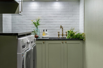Example of a mid-sized eclectic l-shaped terra-cotta tile and multicolored floor laundry room design in San Francisco with an integrated sink, shaker cabinets, green cabinets, soapstone countertops, white backsplash, brick backsplash, green walls, a side-by-side washer/dryer and multicolored countertops