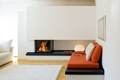 Modernes Wohnzimmer mit weißer Wandfarbe, gebeiztem Holzboden, Eckkamin und verputzter Kaminumrandung in Köln