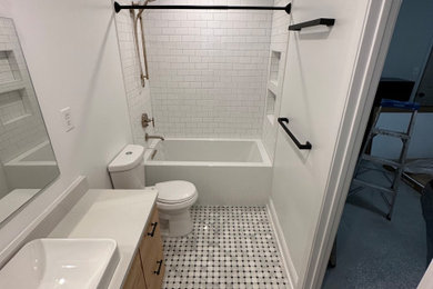 Bathroom - mid-sized transitional white tile and subway tile mosaic tile floor, gray floor and single-sink bathroom idea in New Orleans with shaker cabinets, medium tone wood cabinets, a two-piece toilet, white walls, a vessel sink, white countertops and a built-in vanity