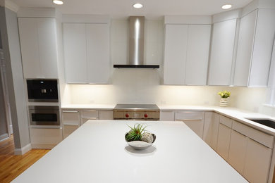 Design ideas for a large scandinavian l-shaped eat-in kitchen in Philadelphia with an undermount sink, flat-panel cabinets, white cabinets, quartz benchtops, white splashback, ceramic splashback, stainless steel appliances, medium hardwood floors, with island and brown floor.