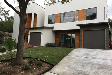 Photo of a large modern two-storey white house exterior in Austin with stone veneer and a flat roof.