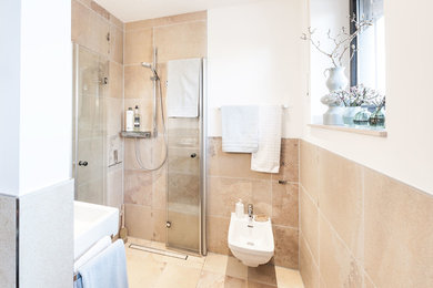 Kleines Landhausstil Duschbad mit beigen Fliesen, weißer Wandfarbe, bodengleicher Dusche, beigem Boden, Falttür-Duschabtrennung, Wandtoilette, Steinfliesen und Wandwaschbecken in Sonstige