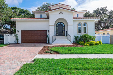 Photo of a large mediterranean two-storey stucco white house exterior in Tampa with a gable roof and a tile roof.
