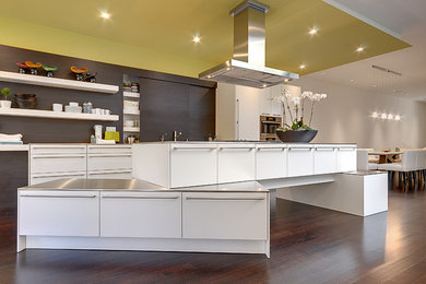 Kitchen - huge contemporary dark wood floor kitchen idea in Toronto with flat-panel cabinets, white cabinets, stainless steel countertops, stainless steel appliances and an island