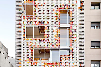 Large trendy multicolored three-story mixed siding flat roof photo in Barcelona