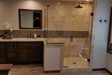 Inspiration for a timeless master beige tile and ceramic tile medium tone wood floor corner shower remodel in Other with an undermount sink, recessed-panel cabinets, dark wood cabinets, beige walls and granite countertops