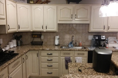 Example of a classic kitchen design in Detroit with raised-panel cabinets, beige cabinets and an island