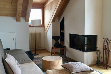 Idée de décoration pour un salon chalet ouvert et de taille moyenne avec un mur blanc, parquet clair et une cheminée d'angle.