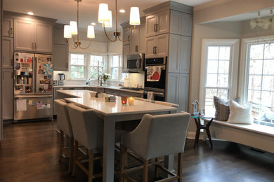 Inspiration for a mid-sized transitional u-shaped medium tone wood floor and brown floor eat-in kitchen remodel in Charlotte with an undermount sink, flat-panel cabinets, gray cabinets, quartz countertops, gray backsplash, porcelain backsplash, stainless steel appliances, an island and white countertops
