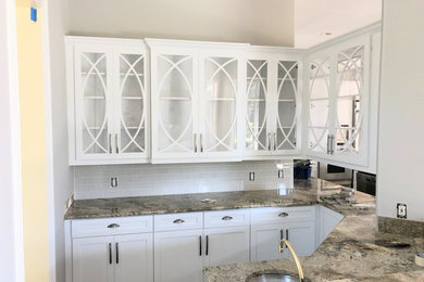 Open concept kitchen - mid-sized transitional porcelain tile and brown floor open concept kitchen idea in Other with a farmhouse sink, shaker cabinets, white cabinets, granite countertops, white backsplash, ceramic backsplash, stainless steel appliances and an island