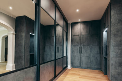 Large gender neutral built-in wardrobe in Buckinghamshire with shaker cabinets, feature lighting, grey cabinets, light hardwood flooring and beige floors.