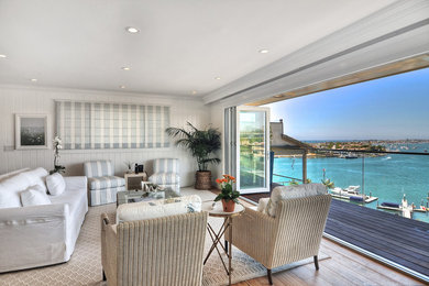 Example of a large beach style open concept medium tone wood floor and brown floor living room design in Orange County with white walls and no fireplace