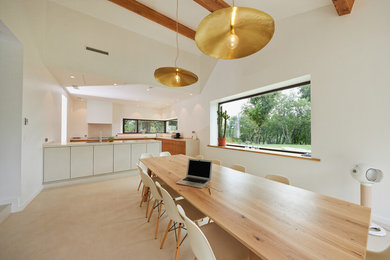 Réalisation d'une très grande salle à manger ouverte sur la cuisine nordique avec sol en béton ciré et un sol blanc.