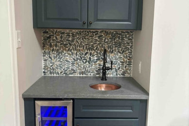 Example of a small minimalist single-wall wet bar design in Philadelphia with an undermount sink, raised-panel cabinets, blue cabinets, quartz countertops, multicolored backsplash, stone tile backsplash and gray countertops