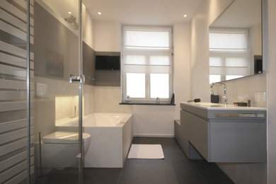 Großes Modernes Badezimmer mit flächenbündigen Schrankfronten, grauen Schränken, weißen Fliesen, weißer Wandfarbe, Keramikboden und grauem Boden