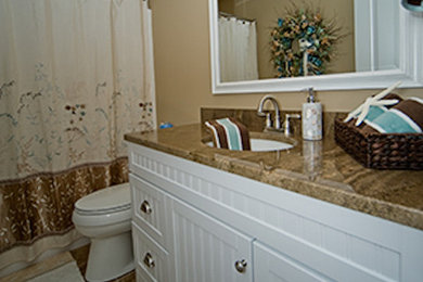 Brown tile bathroom photo in Boston with white cabinets, granite countertops and beige walls