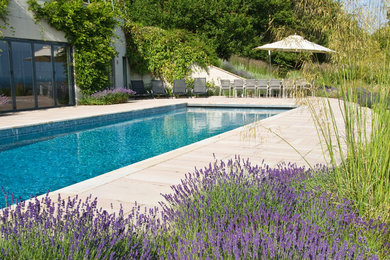 Inspiration for a large contemporary backyard rectangular lap pool in Sussex with natural stone pavers.