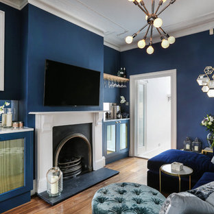 Eclectic enclosed family and games room in London with a home bar, blue walls, medium hardwood flooring, a standard fireplace and a wall mounted tv.
