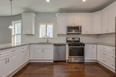 Inspiration for a mid-sized timeless u-shaped dark wood floor and brown floor kitchen remodel in Boston with an undermount sink, raised-panel cabinets, white cabinets, granite countertops, white backsplash, ceramic backsplash, stainless steel appliances, no island and multicolored countertops