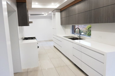 Mid-sized contemporary galley eat-in kitchen in Sydney with a double-bowl sink, flat-panel cabinets, white cabinets, marble benchtops, yellow splashback, with island and white benchtop.