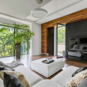 Modern Living Room With Big White Corner Sofa and Forest View Behind Window Wall