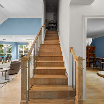Straight-on view of an open staircase with wood treads and iron balusters.
