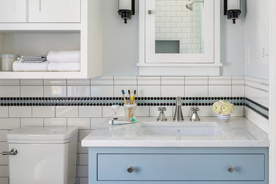 Small traditional kids bathroom in Minneapolis with blue cabinets, a corner shower, a two-piece toilet, black and white tile, ceramic tile, blue walls, marble floors, an undermount sink, engineered quartz benchtops, grey floor, a hinged shower door, white benchtops and shaker cabinets.