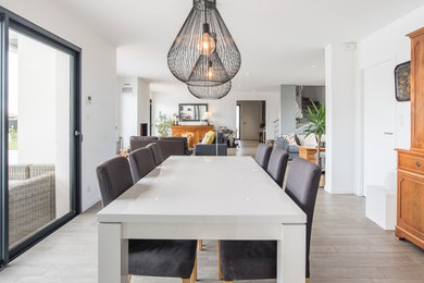 Large contemporary open plan dining in Toulouse with white walls, a standard fireplace and grey floor.