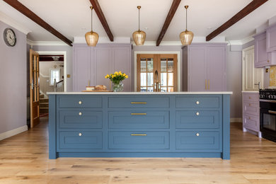 Inspiration for a mid-sized traditional u-shaped kitchen in Kent with a double-bowl sink, shaker cabinets, purple cabinets, quartzite benchtops, yellow splashback, ceramic splashback, stainless steel appliances, light hardwood floors, with island, beige floor, white benchtop and exposed beam.