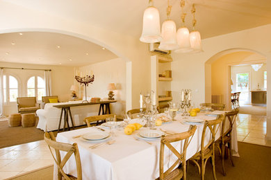 Modelo de comedor mediterráneo grande abierto sin chimenea con paredes amarillas y suelo de baldosas de cerámica