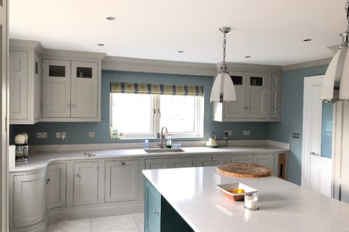 This is an example of a large contemporary l-shaped eat-in kitchen in Other with an integrated sink, raised-panel cabinets, grey cabinets, marble benchtops, grey splashback, glass sheet splashback, stainless steel appliances, porcelain floors, with island, grey floor and white benchtop.