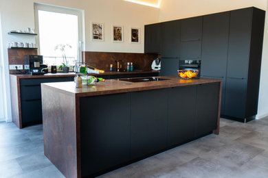 Offene, Große Industrial Küche in L-Form mit schwarzen Schränken, Küchenrückwand in Braun, Kücheninsel und brauner Arbeitsplatte in Sonstige