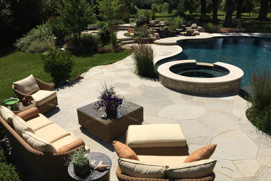 Large arts and crafts backyard custom-shaped natural pool in Chicago with a hot tub and natural stone pavers.