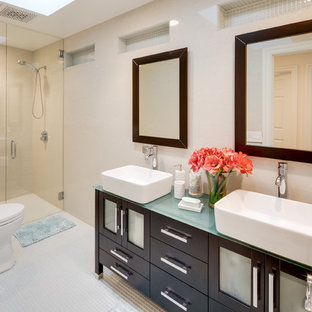 Inspiration for a mid-sized timeless 3/4 mosaic tile floor and beige floor walk-in shower remodel in San Diego with furniture-like cabinets, dark wood cabinets, a two-piece toilet, beige walls, a vessel sink, glass countertops and a hinged shower door