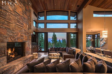 Large country open concept living room in Other with beige walls, dark hardwood floors, a standard fireplace, a stone fireplace surround, a wall-mounted tv and brown floor.