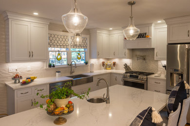 Example of a large transitional l-shaped light wood floor and brown floor enclosed kitchen design in Boston with a farmhouse sink, beaded inset cabinets, white cabinets, quartz countertops, white backsplash, porcelain backsplash, stainless steel appliances, an island and white countertops