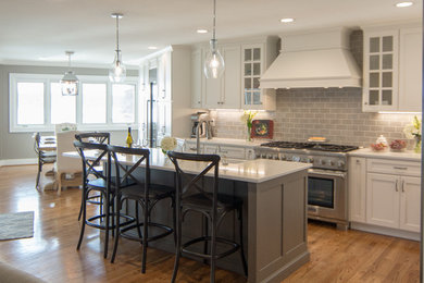 Inspiration for a large timeless l-shaped medium tone wood floor and brown floor eat-in kitchen remodel in Other with a farmhouse sink, recessed-panel cabinets, white cabinets, quartzite countertops, gray backsplash, subway tile backsplash, stainless steel appliances and an island