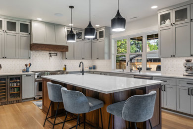 Large arts and crafts l-shaped light wood floor and brown floor open concept kitchen photo in Seattle with an undermount sink, shaker cabinets, gray cabinets, quartz countertops, multicolored backsplash, ceramic backsplash, stainless steel appliances, an island and white countertops