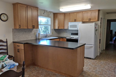 Eat-in kitchen - mid-sized transitional u-shaped linoleum floor and multicolored floor eat-in kitchen idea in Other with a double-bowl sink, recessed-panel cabinets, light wood cabinets, laminate countertops, gray backsplash, ceramic backsplash, white appliances, a peninsula and black countertops