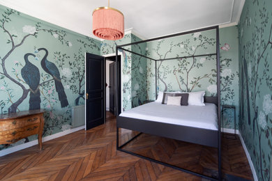 Idée de décoration pour une grande chambre parentale design avec un mur vert, un sol en bois brun, un sol marron et du papier peint.