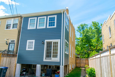This is an example of a mid-sized three-storey blue townhouse exterior in DC Metro with concrete fiberboard siding and a flat roof.
