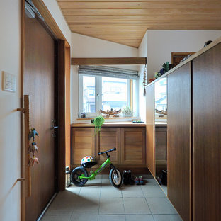 他の地域の片開きドアアジアンスタイルのおしゃれな玄関ラウンジ (白い壁、木目調のドア、グレーの床) の写真