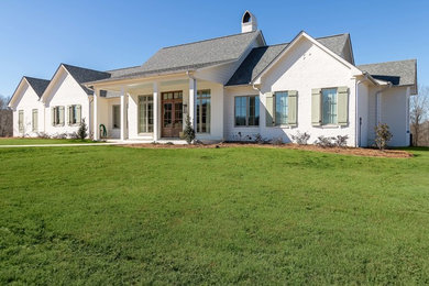 Example of a large cottage white one-story brick exterior home design in Jackson with a shingle roof