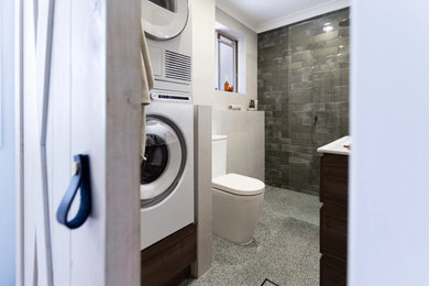 This is an example of a small contemporary 3/4 bathroom in Sydney with flat-panel cabinets, dark wood cabinets, an open shower, a two-piece toilet, green tile, white walls, an integrated sink, multi-coloured floor, an open shower, white benchtops, a laundry, a single vanity and a freestanding vanity.